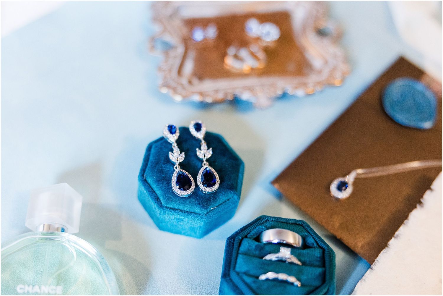 Close-up of wedding jewelry and rings displayed in bright blue hexagonal boxes.