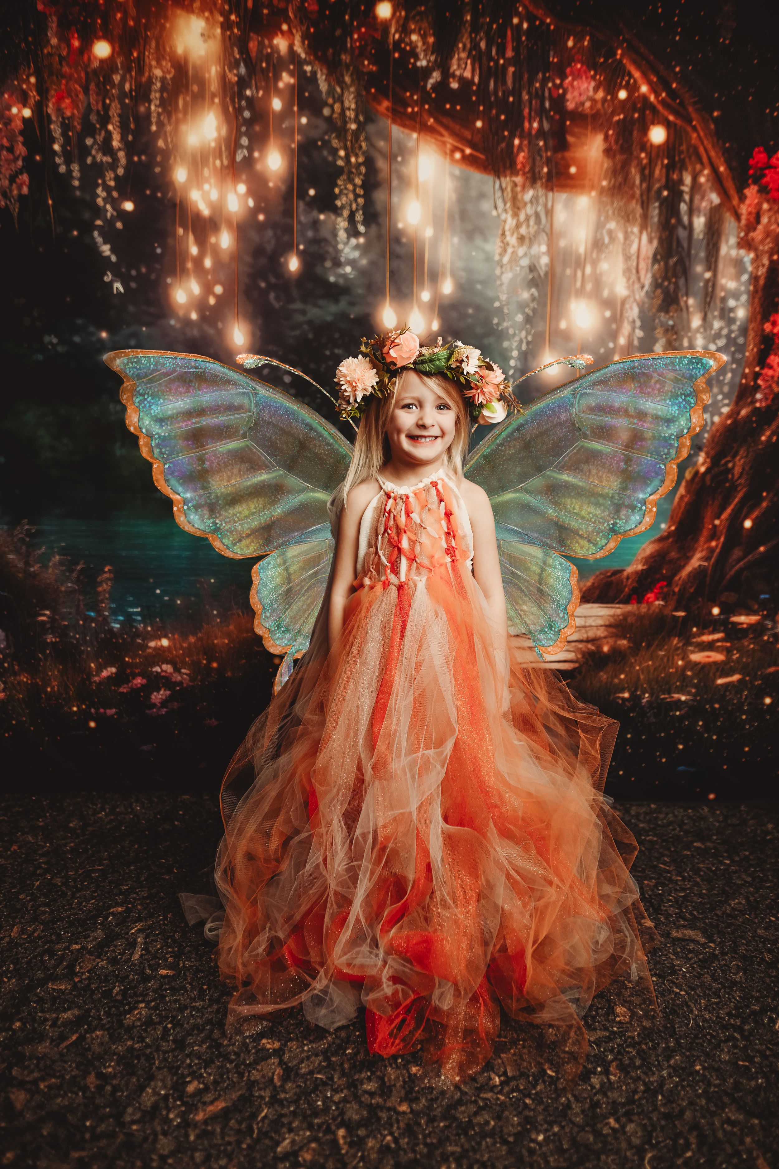 Enchanted forest photoshoot with fairy wings and flowing orange dress.