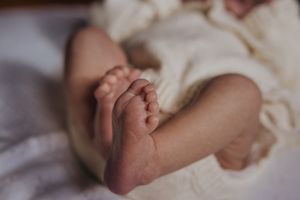 A series of black and white photographs showing tiny newborn baby feet against a soft white background.