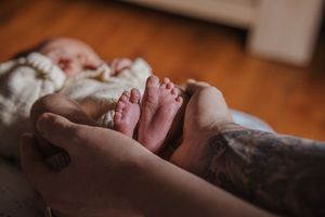 A series of close-up photos showing a newborn baby's tiny hands and feet against a warm wooden background.
