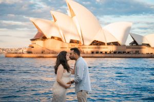 Iconic Sydney Opera House glows with warm sunset light against blue harbor waters.