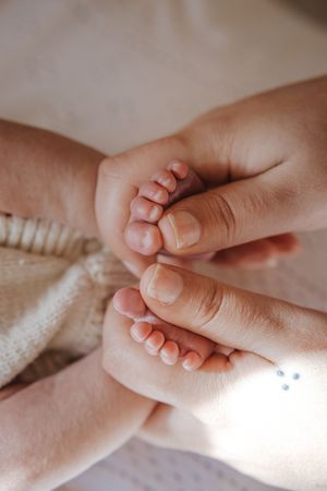 Close-up photo series of a tiny baby's hand holding an adult's finger against a soft white blanket background.