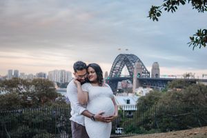 Romantic maternity photoshoot with city skyline and Sydney Harbour Bridge in the background at sunset.