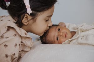 A series of tender moments showing a parent and child cuddling together in bed with white linens.
