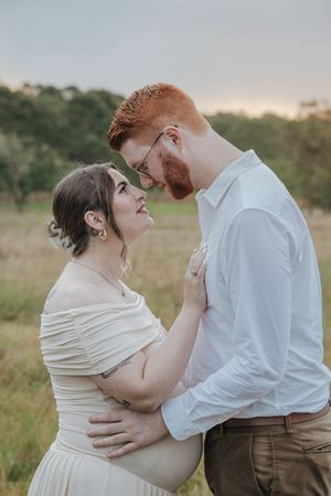 A romantic couple embraces in a sunlit meadow during a dreamy outdoor photoshoot.