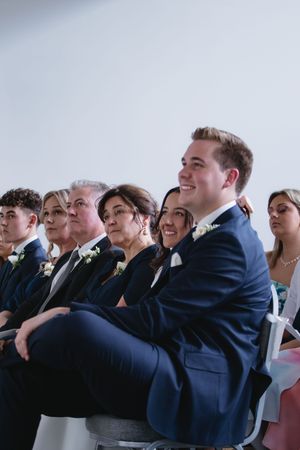 Wedding guests share laughter and joy while seated in rows during a ceremony.