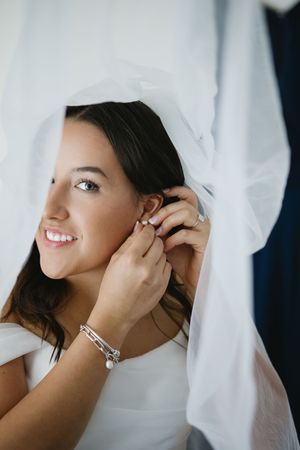 A series of close-up shots showing someone putting on earrings while wearing white fabric.