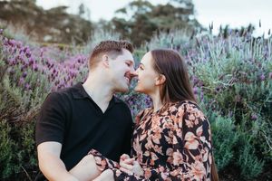 A couple shares romantic moments in a garden filled with blooming lavender and wildflowers during a sunset photoshoot.