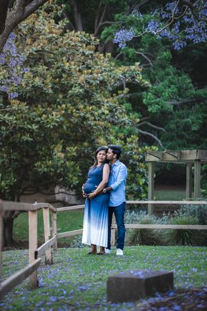 Romantic outdoor photoshoot among blooming purple flowers and lush greenery in a garden setting.
