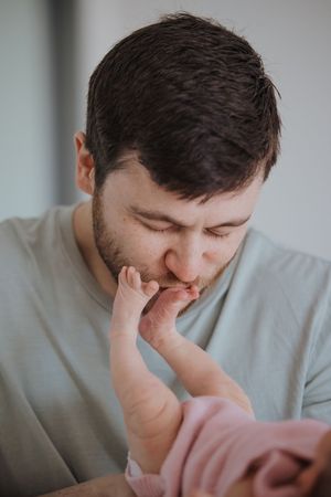 A person in a light gray sweater shows emotional distress while covering their face with their hands.