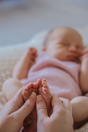 Gentle hands massage tiny baby feet against a soft beige background in a series of tender moments.