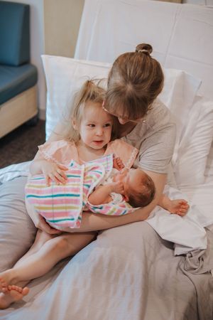 A tender family moment showing affection and bonding on a white bed with colorful striped clothing.