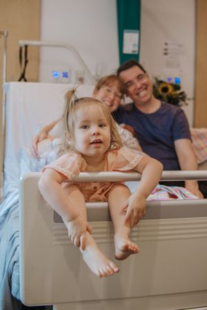 A playful scene in a medical setting with family members interacting near hospital equipment.