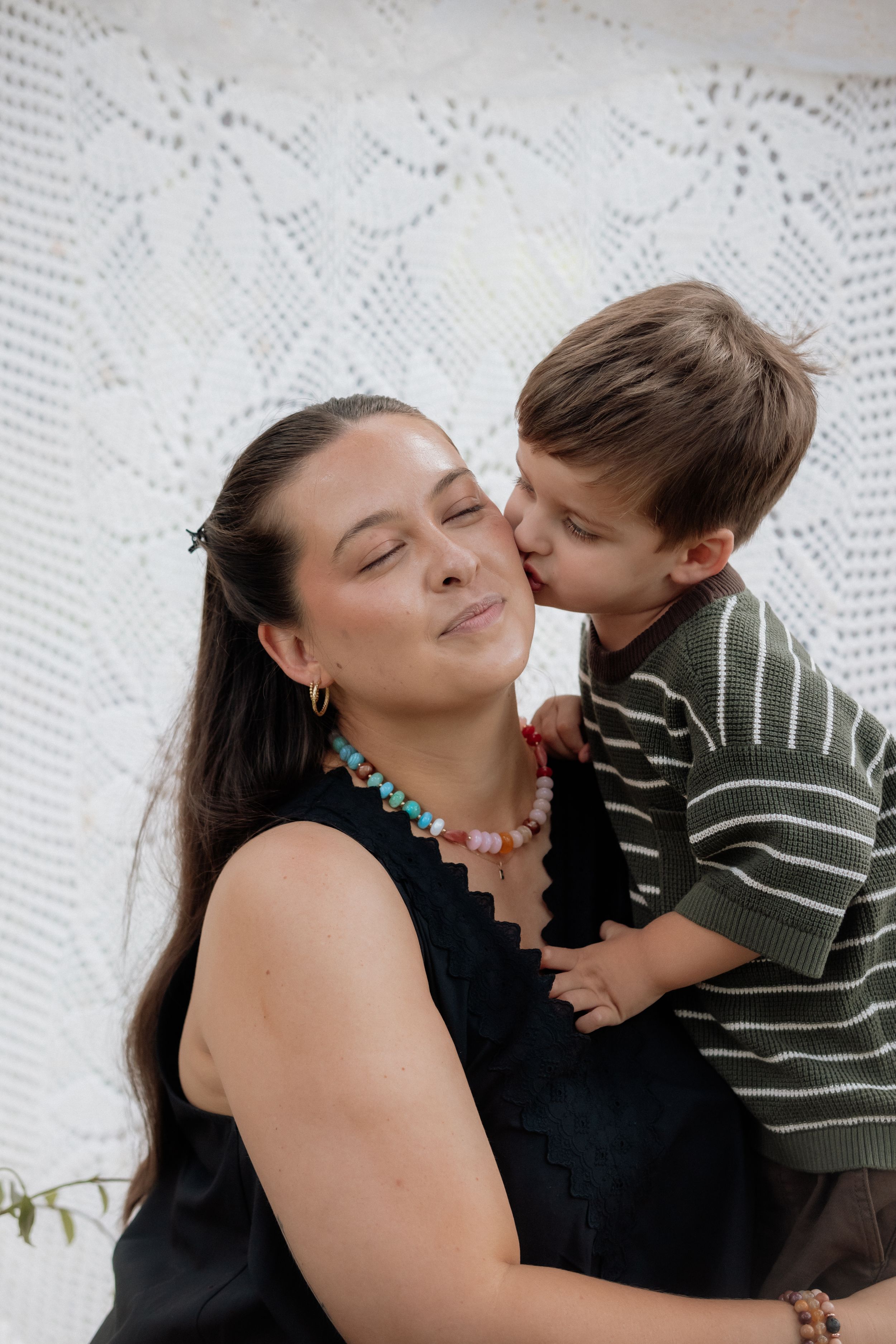 A sweet moment of affection between a parent and child against a white lace background.