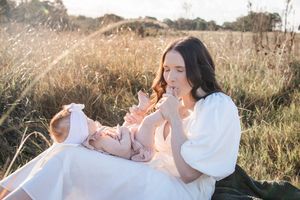 A couple embraces in a golden field during sunset, creating a romantic and dreamy outdoor portrait.