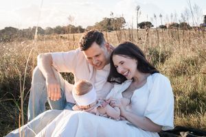 A couple in white outfits shares tender moments together in a sunlit meadow during a golden hour photoshoot.