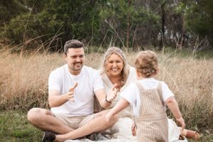 Happy family enjoying a candid moment together while sitting on grass in a field.