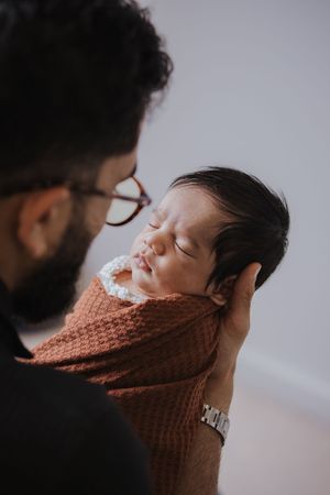 A tender moment captured in a series of photos showing a sleeping baby wrapped in a rust-colored knit blanket.