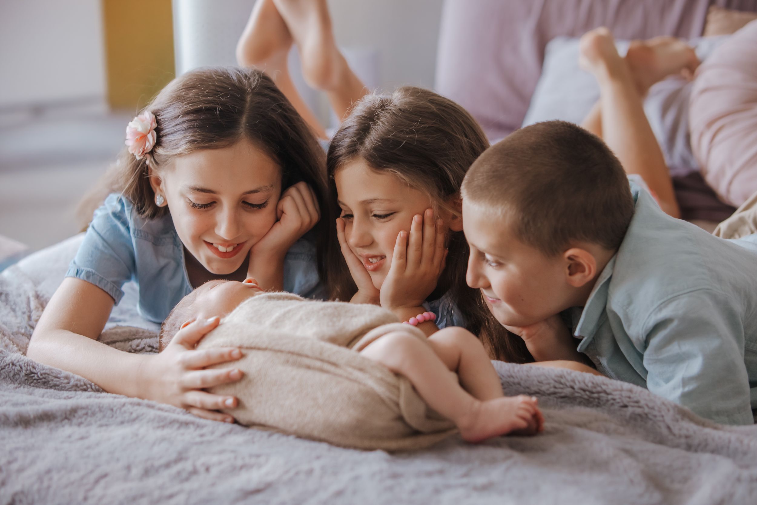 A series of photos showing people lying on a bed together, sharing tender family moments in soft lighting.