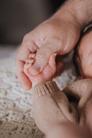 Close-up shot of tiny baby feet wearing beige knit socks against a textured cream background.