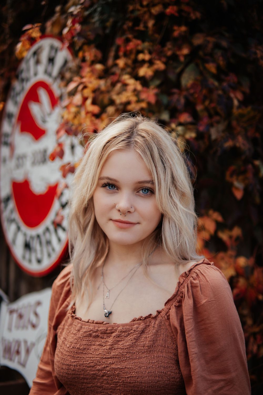 A rustic autumn scene with fall foliage and vintage signage in the background.