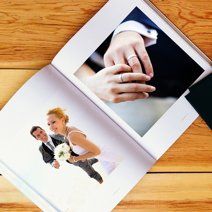 Wedding photo album open to page showing couple's hands with rings.