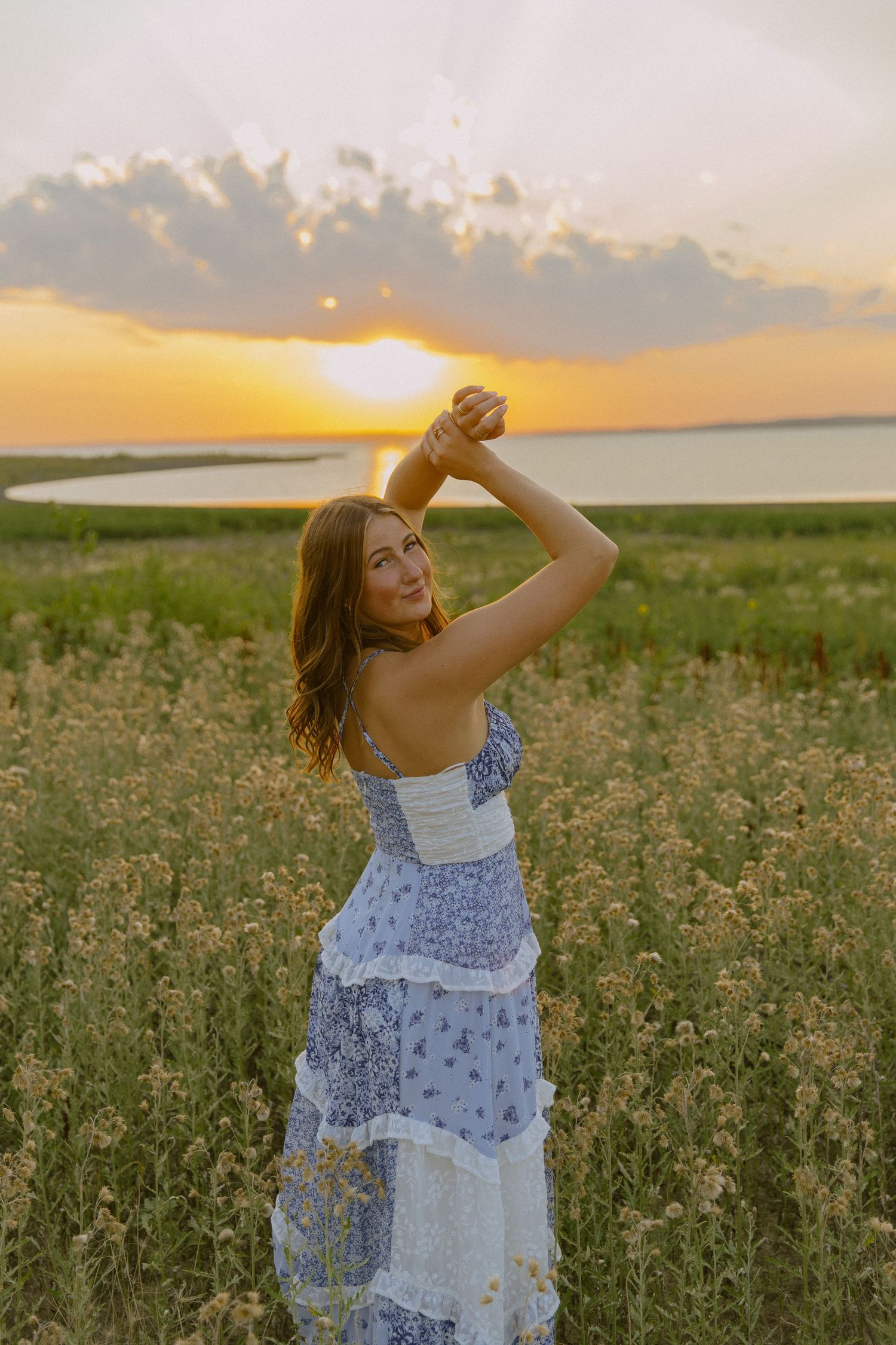 Woman in floral dress twirling in a wildflower field at golden hour.