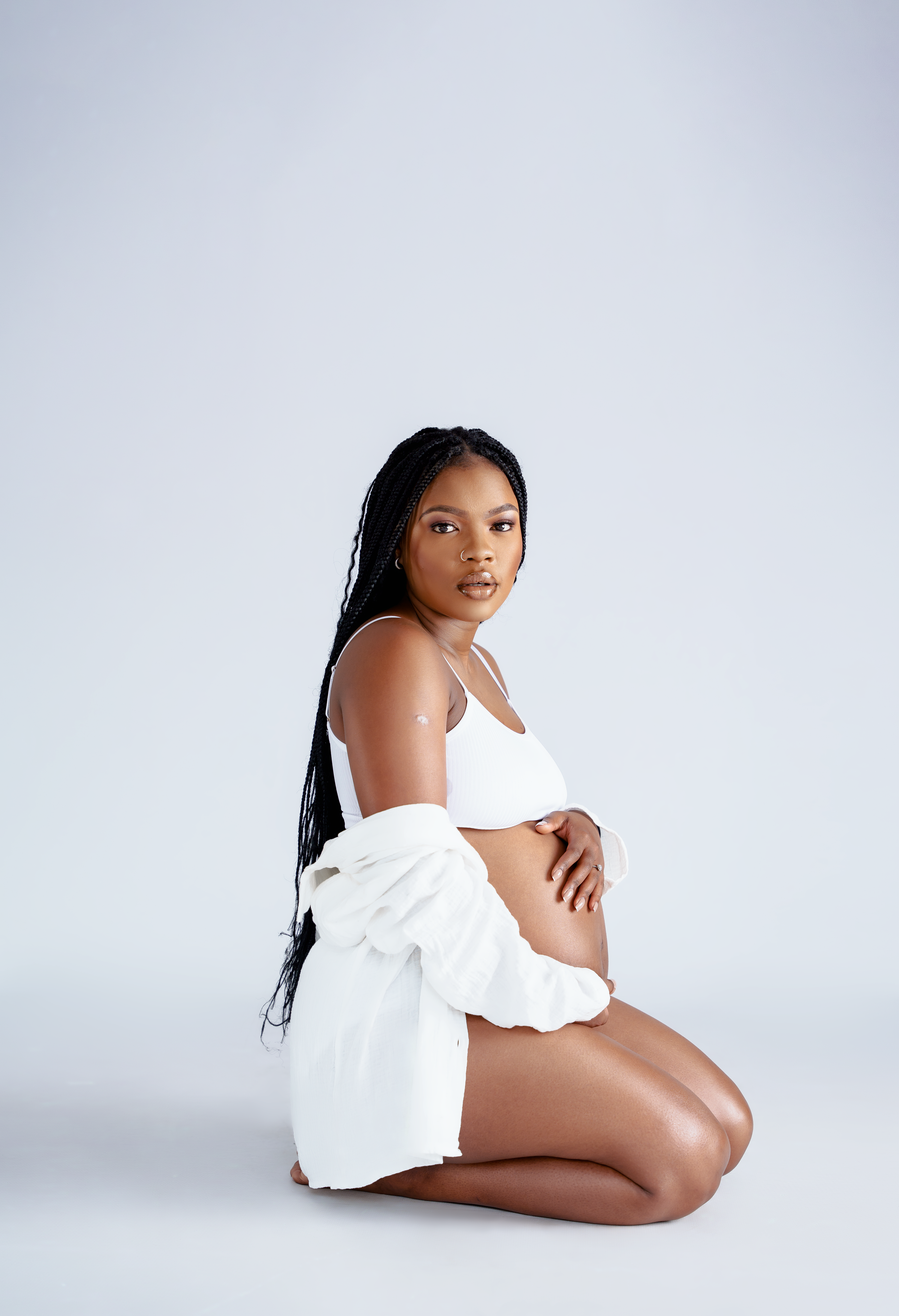Side view of pregnant woman in white clothing during professional photoshoot.