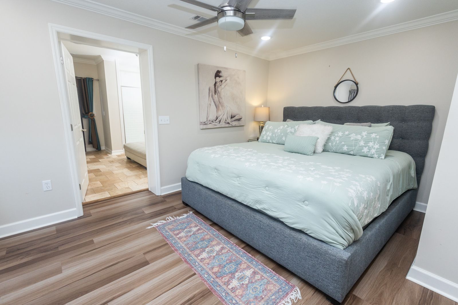 Bedroom with gray bed frame and mint green bedding on hardwood floors.