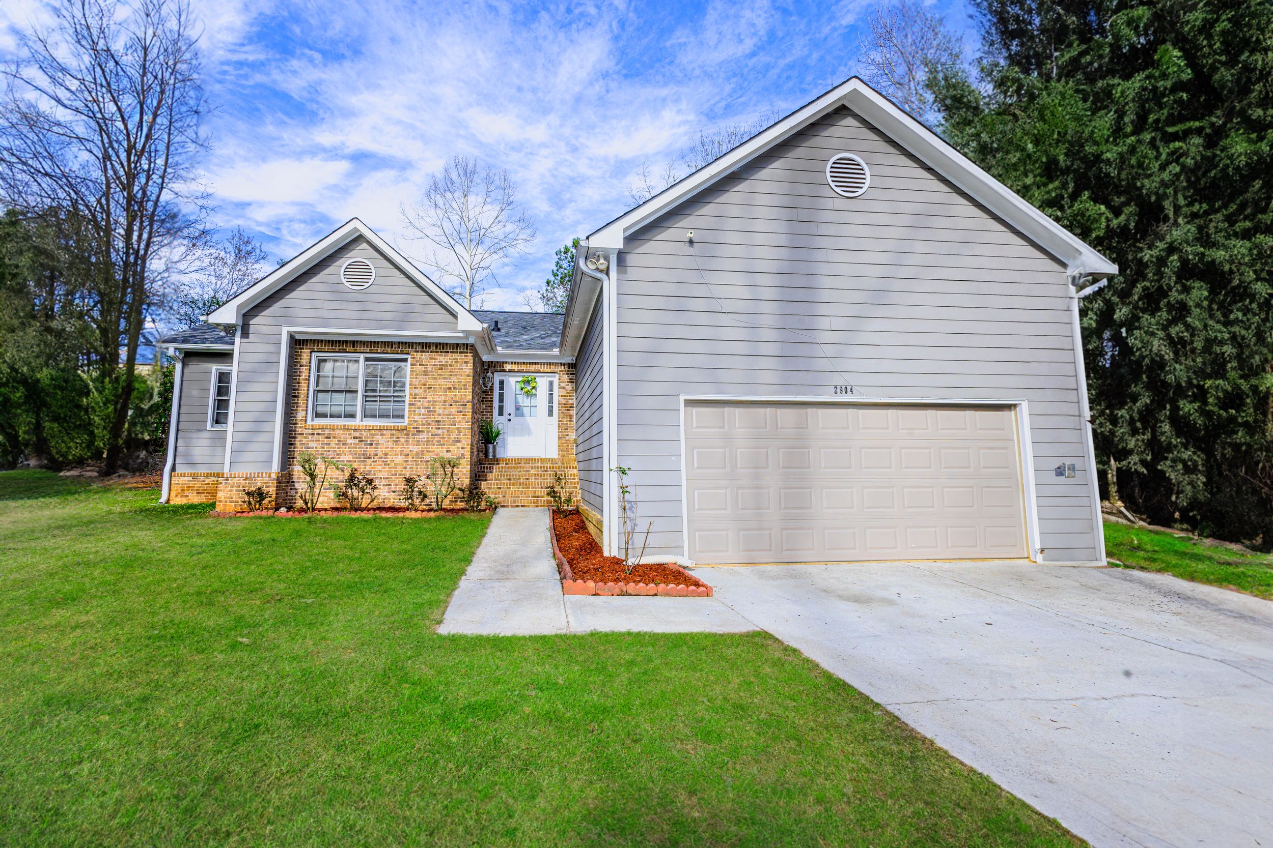 Row of modern single-story homes with garages and driveways viewed from above.