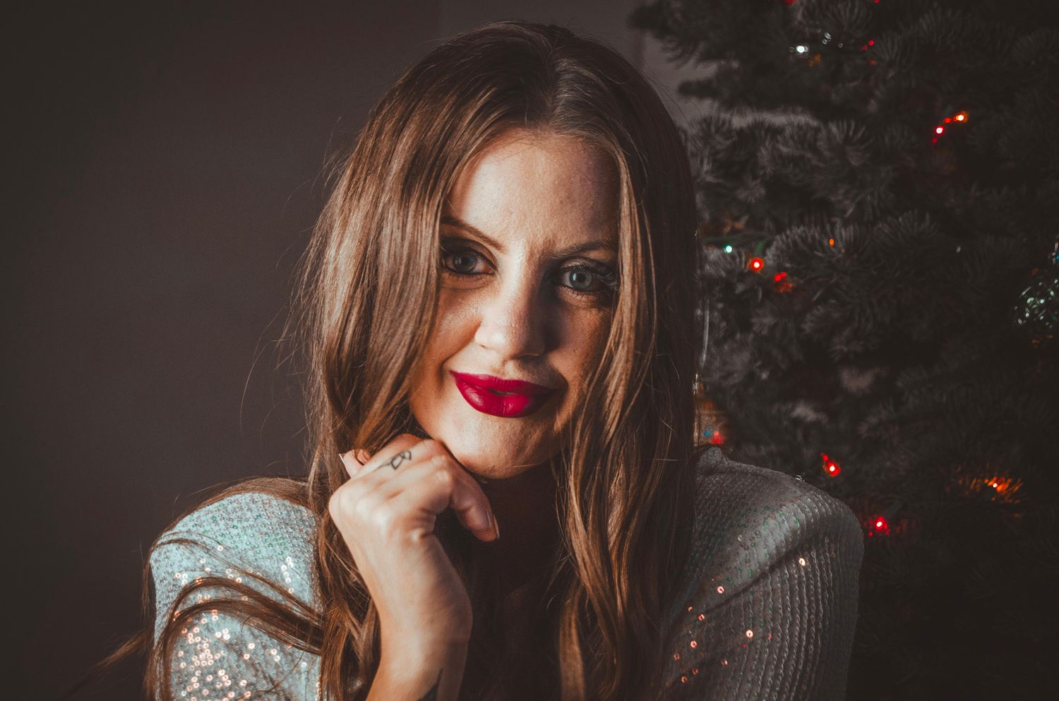 Moody Christmas portraits with red lighting and decorative elements in dark setting.