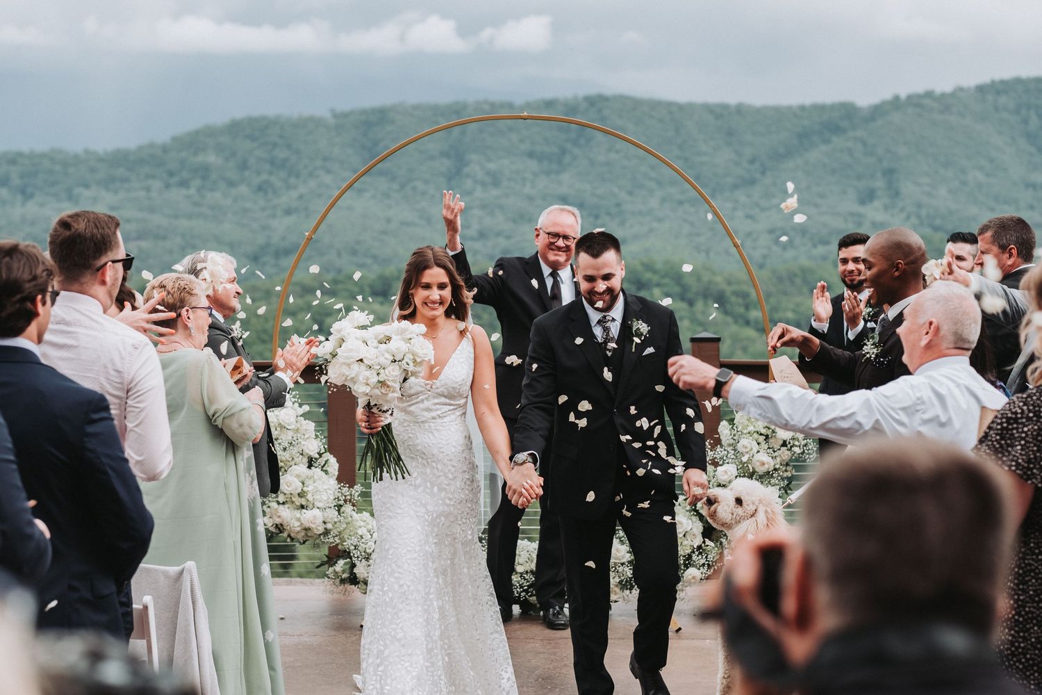 Wedding ceremony at a scenic mountain venue with guests celebrating as bubbles float through the air during recessional.