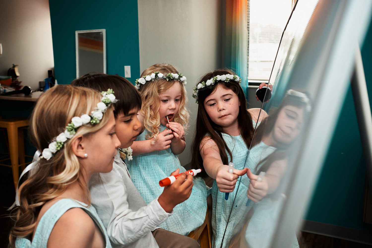 Young bridesmaids in flower crowns and blue dresses get ready together before a wedding.