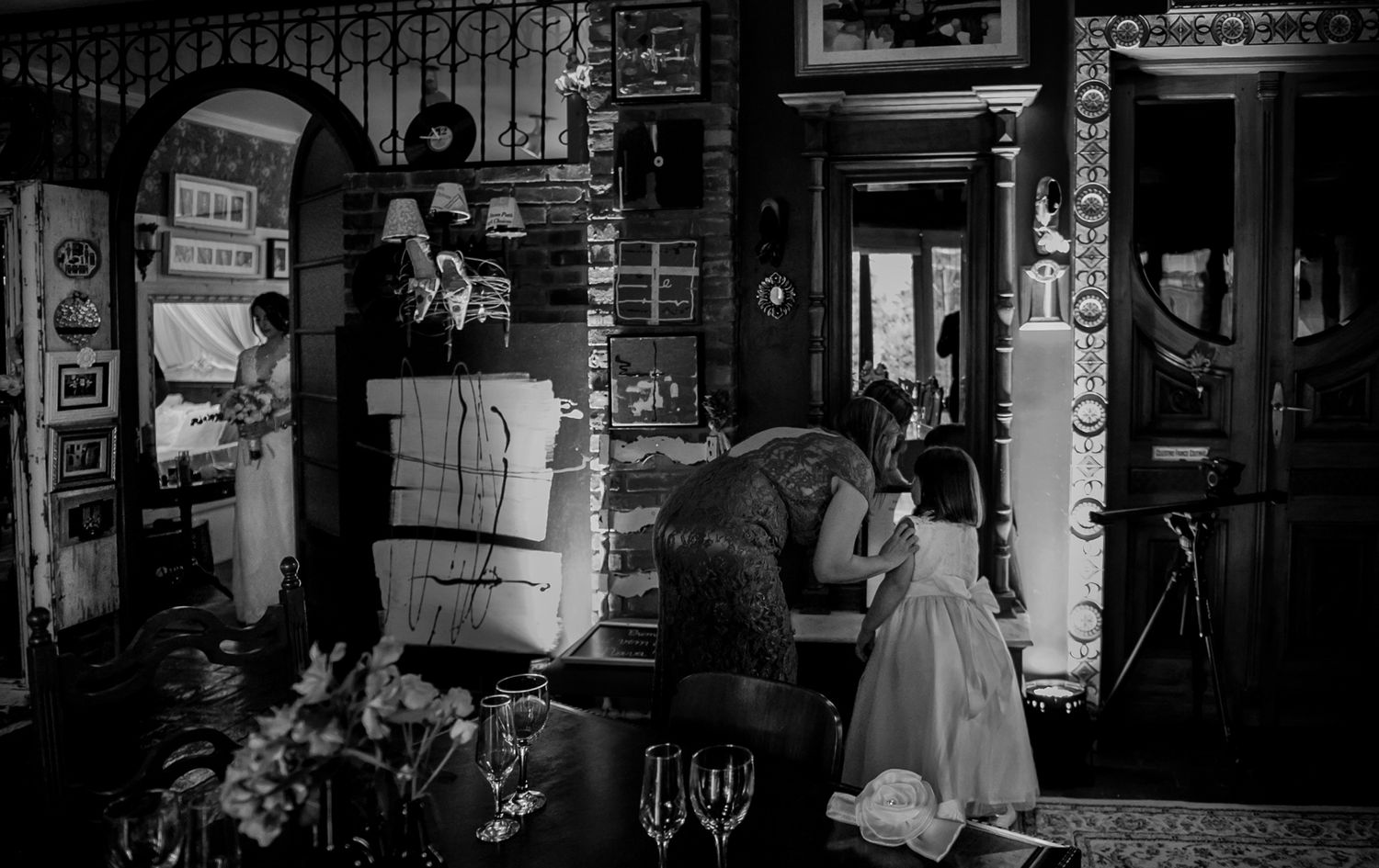 Black and white vintage scene of people in front of an old store or shop entrance.