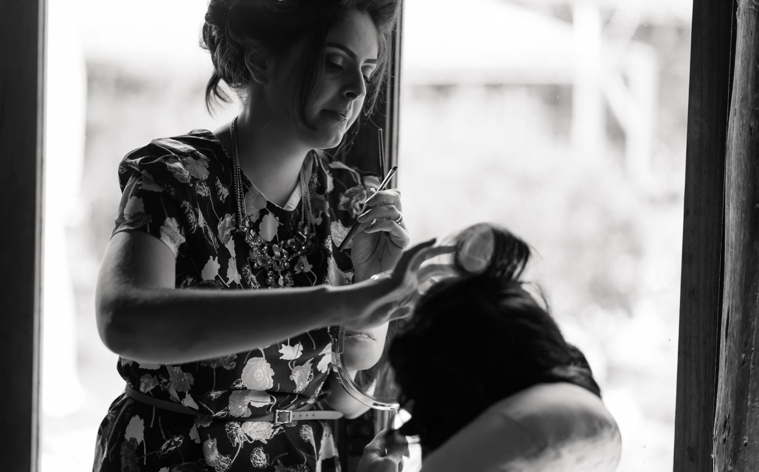 Intimate black and white portrait of someone in a floral dress preparing for a special occasion.