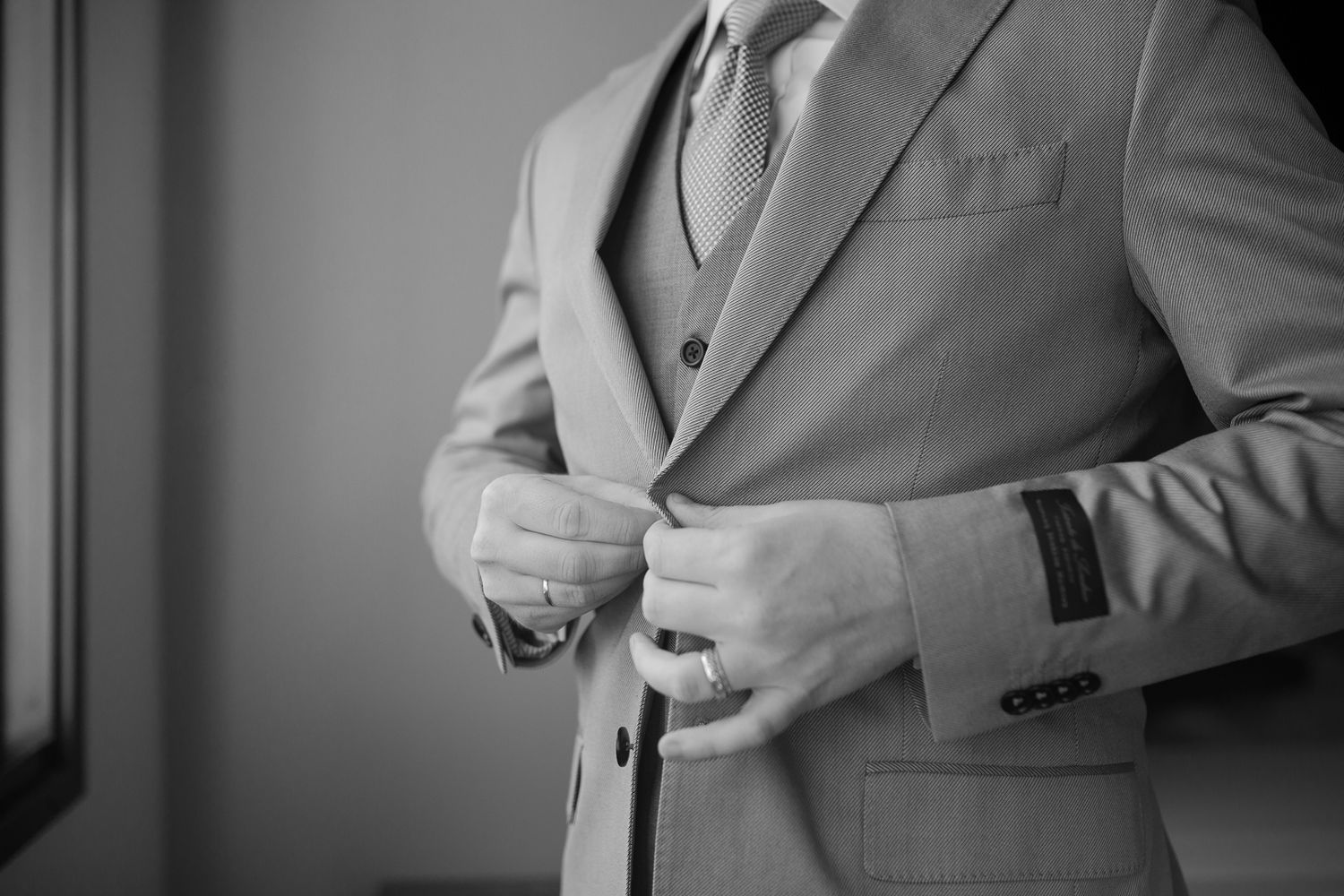 Close-up of formal grey suit jacket being adjusted in monochrome.