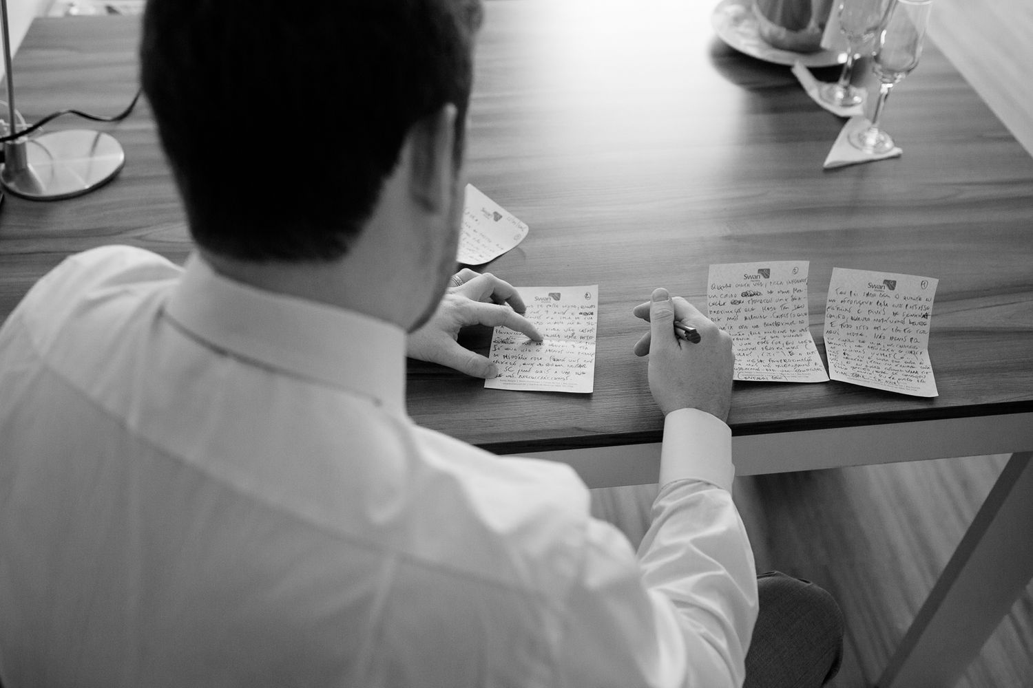 Person writing wedding vows or speech at desk with papers spread out.