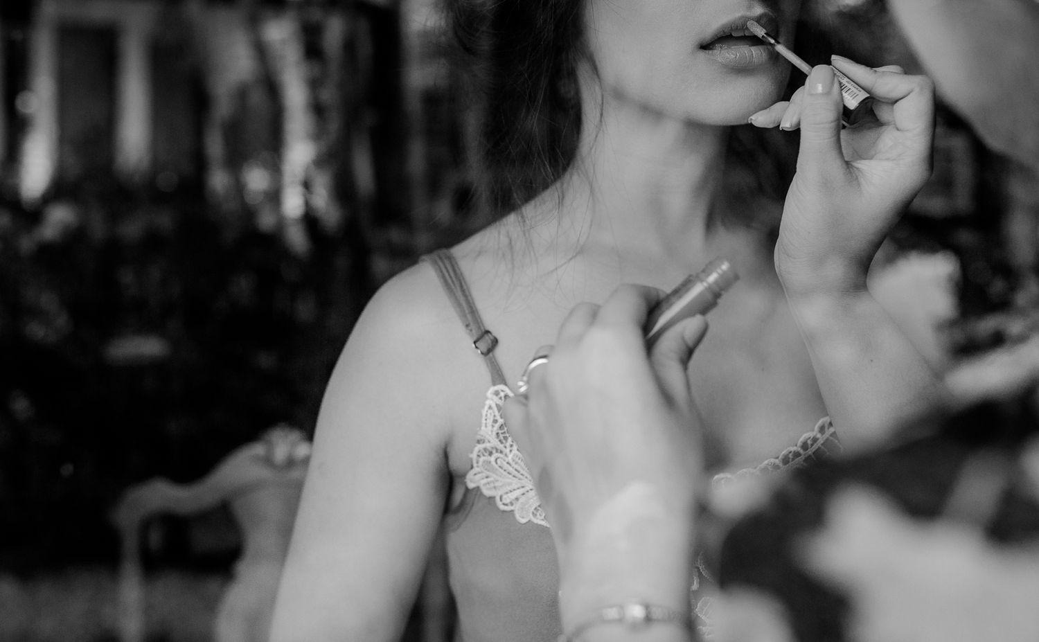 Black and white close-up shot of makeup application in dramatic lighting.
