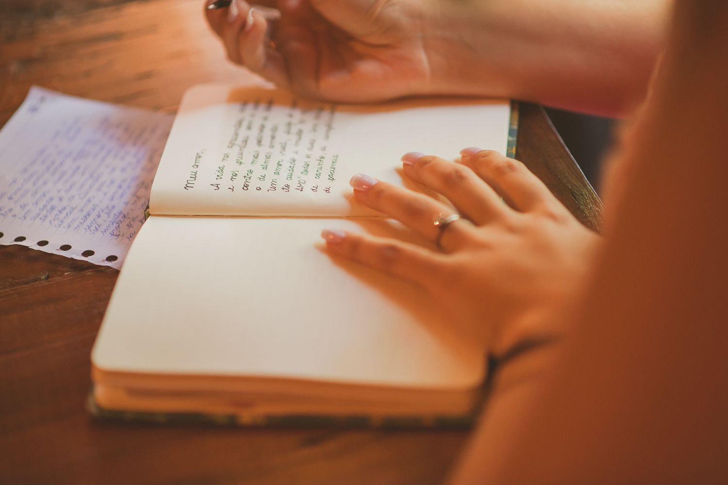 Hands resting on open book pages in warm natural lighting.