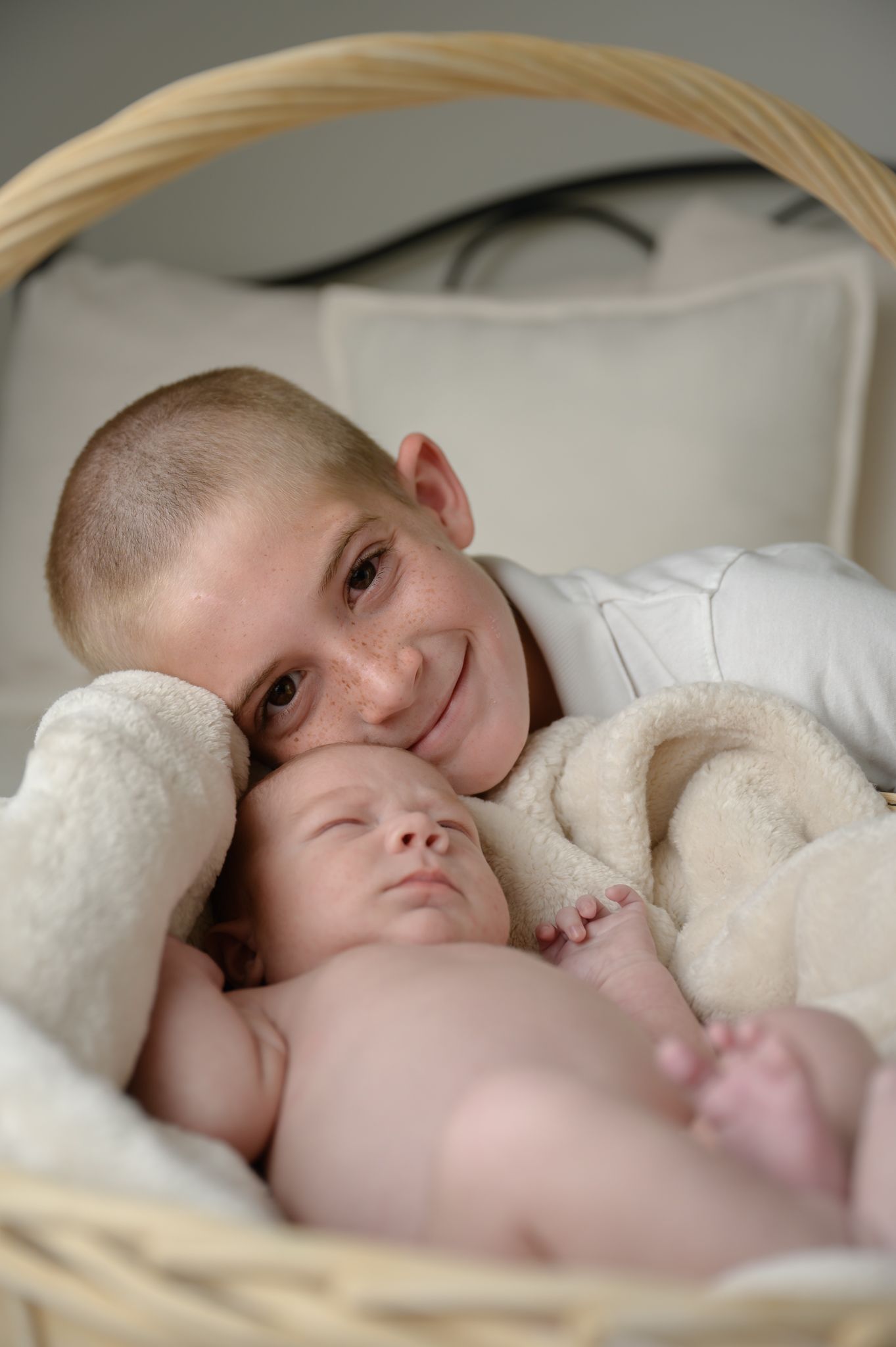 Two children resting together in a cozy white basket with soft blankets.