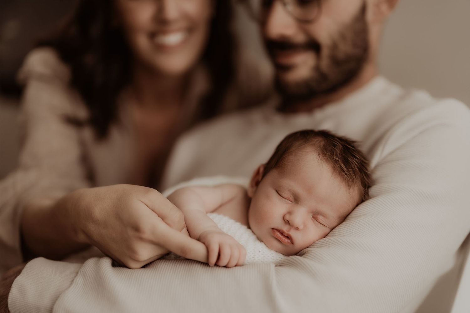 Intimate indoor family moment in soft sepia tones.