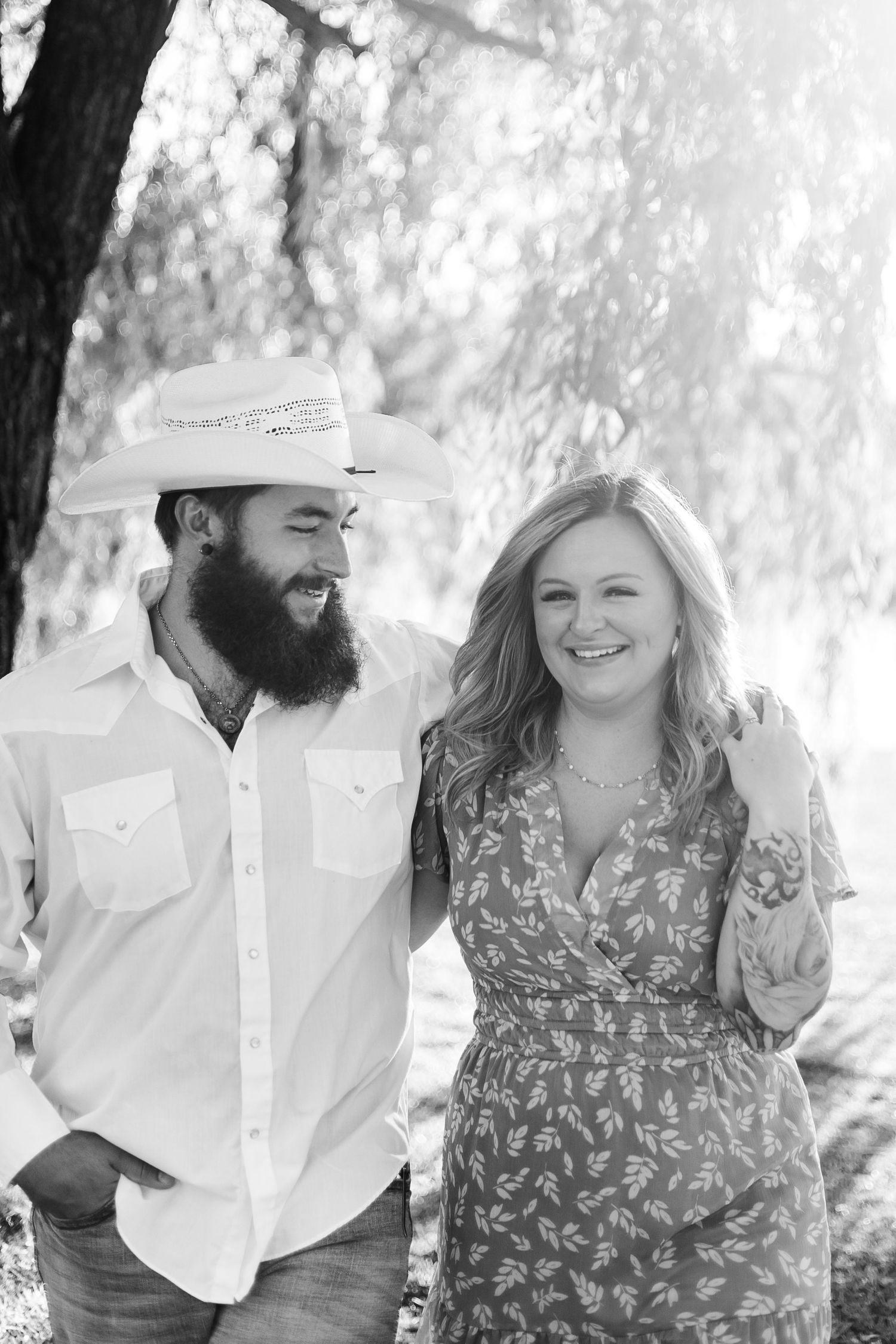Couple laughing together during outdoor photo session under willow trees.