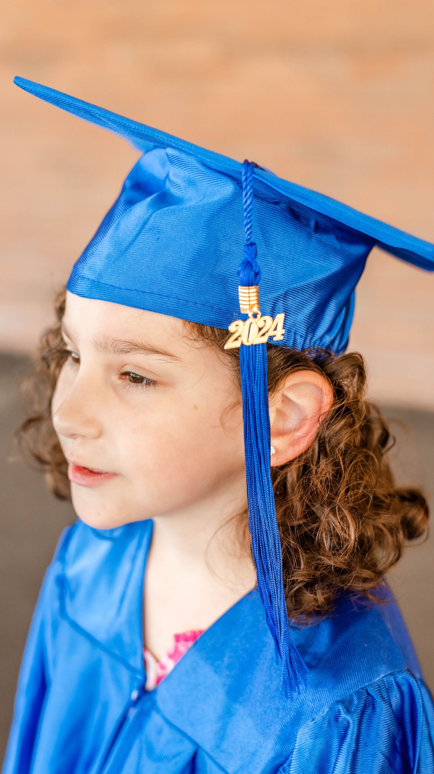 Student in blue graduation cap and gown with 2024 tassel shown in profile.