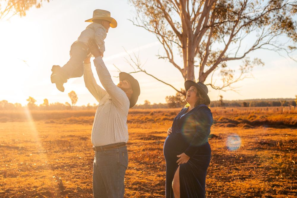 Joyful family moment at sunset with baby toss in outback setting.
