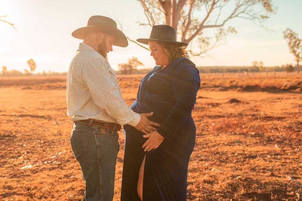 Couple in western attire sharing intimate moment at golden hour.