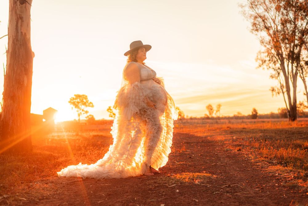 Silhouette of person in cowboy hat and flowing dress at sunset.