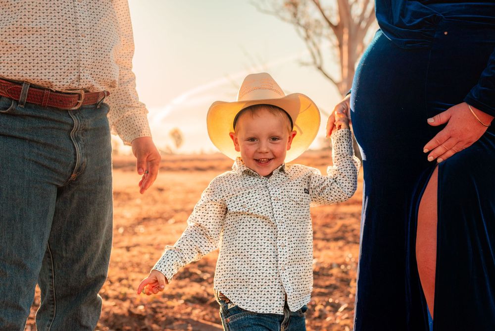 A child wearing a cowboy hat stands outdoors during golden hour in the Australian outback.