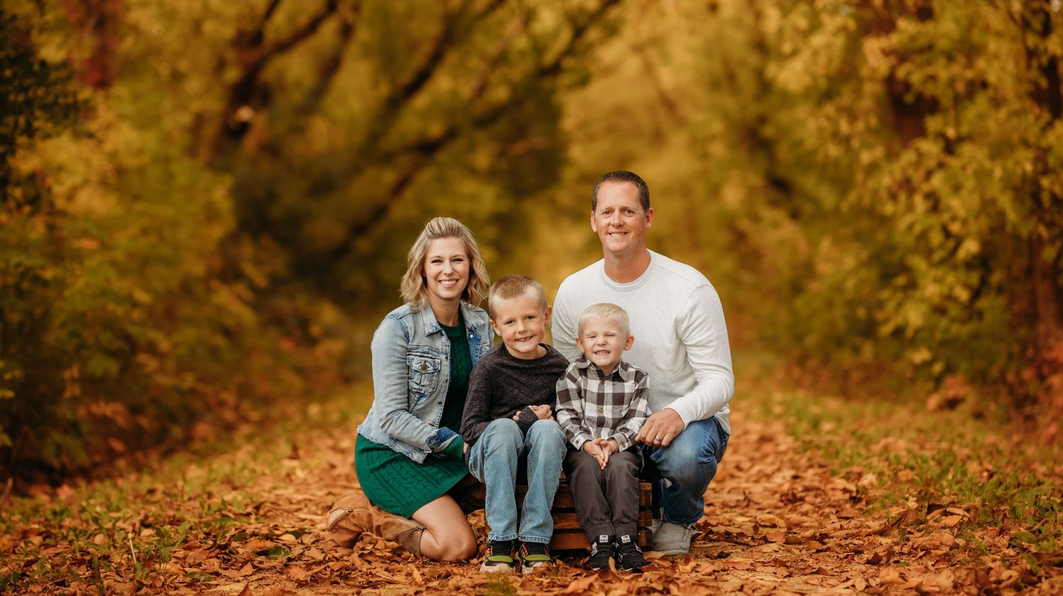 Family portrait with fall foliage backdrop and golden autumn leaves.