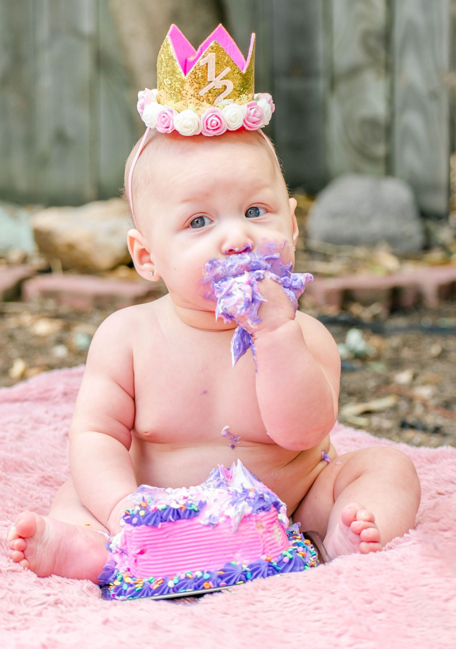 Baby wearing crown and purple tutu outfit for milestone photo session.