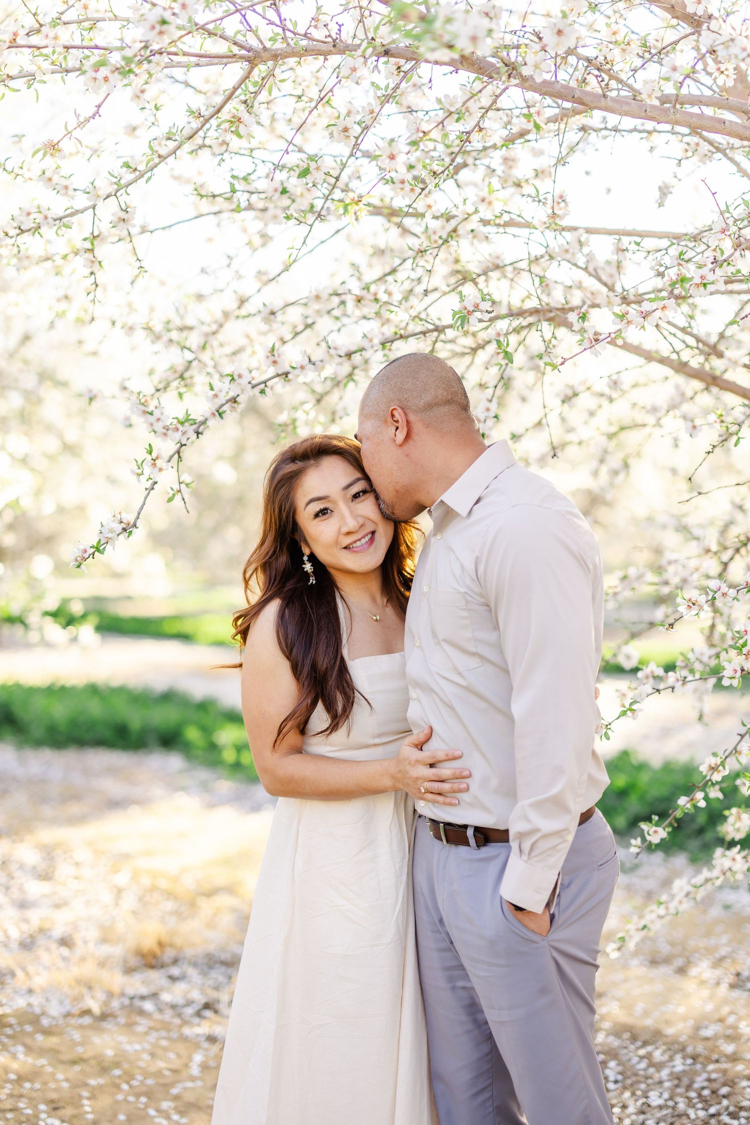 Romantic couple's portrait session in casual attire against sunlit natural background.